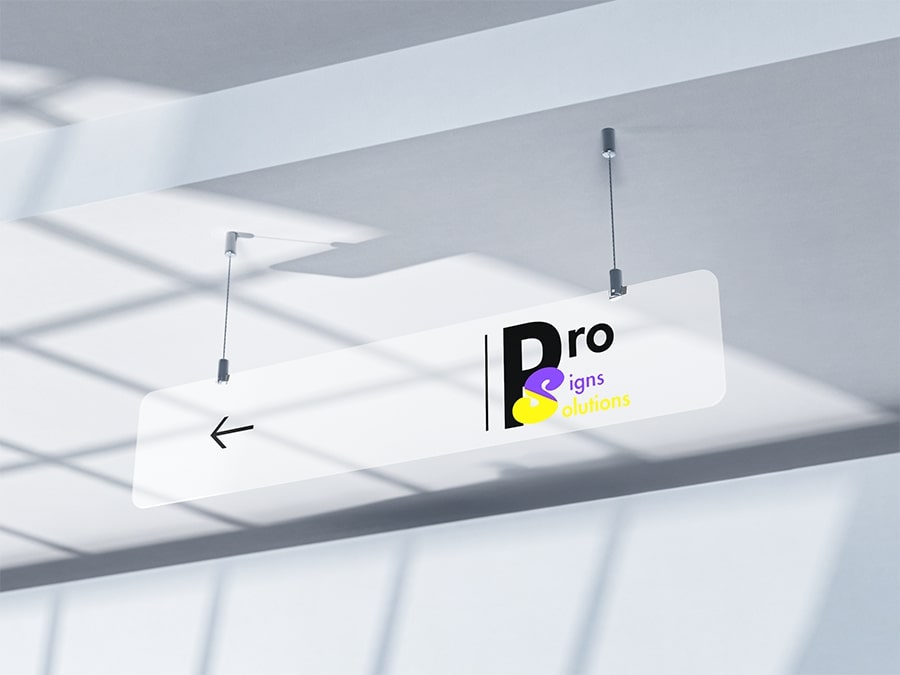 ro Signs Solutions logo displayed on a clear acrylic suspended sign hanging from the ceiling with metal cables, featuring a left-pointing directional arrow.
